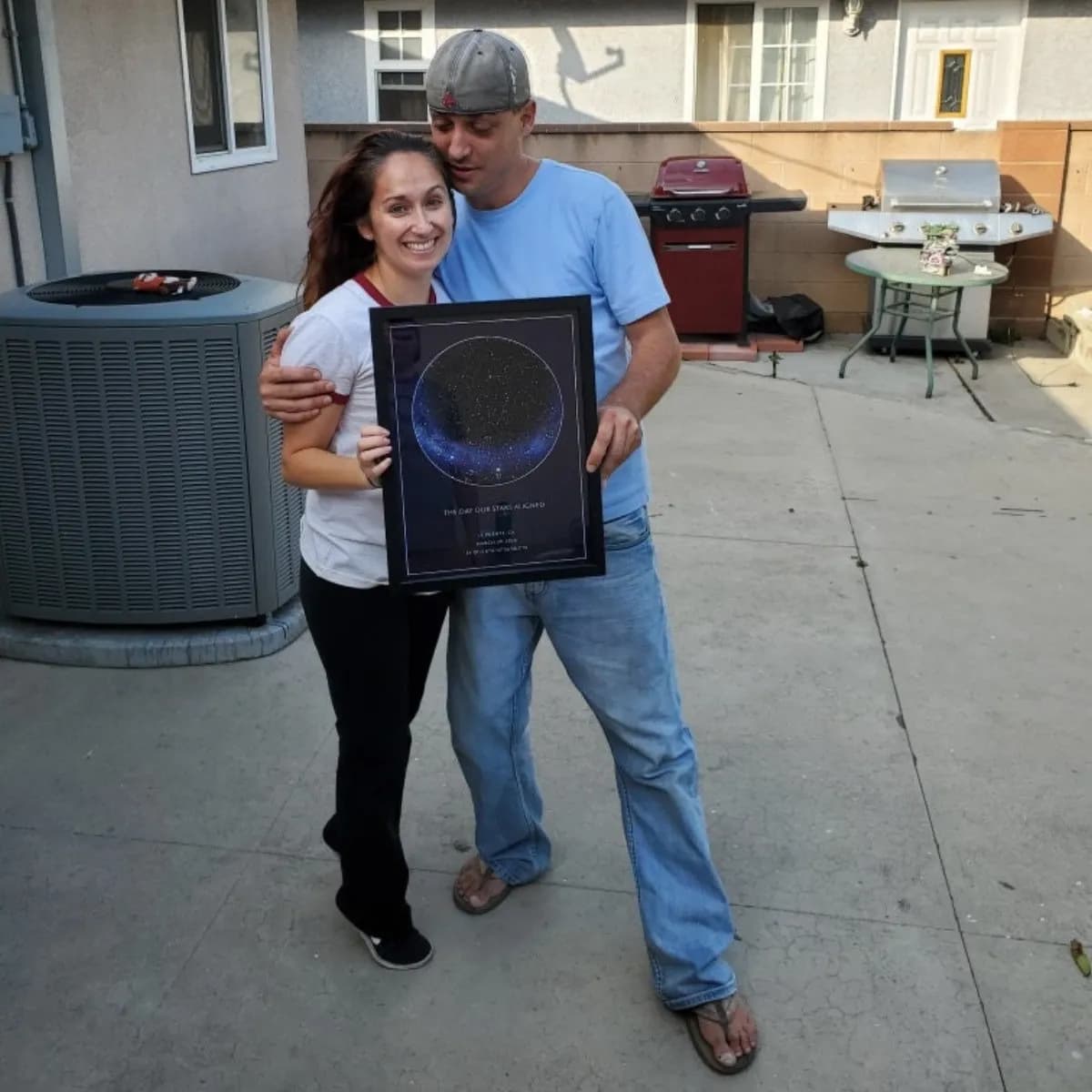Couple holding a star map poster in their backyard